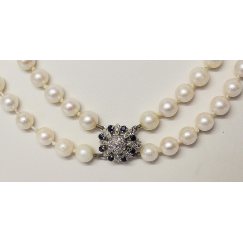 646 - A double uniform row of cultured pearls to a white gold sapphire and diamond circular cluster clasp.... 