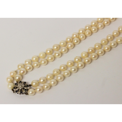 646 - A double uniform row of cultured pearls to a white gold sapphire and diamond circular cluster clasp.... 