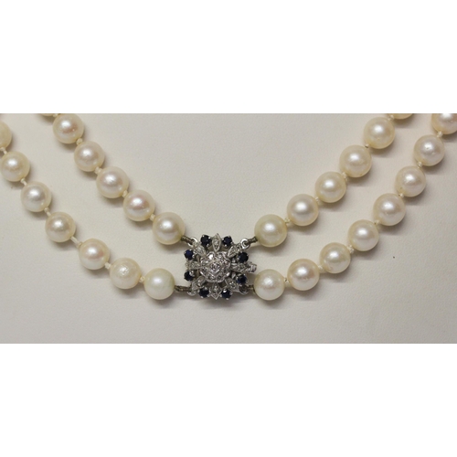 646 - A double uniform row of cultured pearls to a white gold sapphire and diamond circular cluster clasp.... 