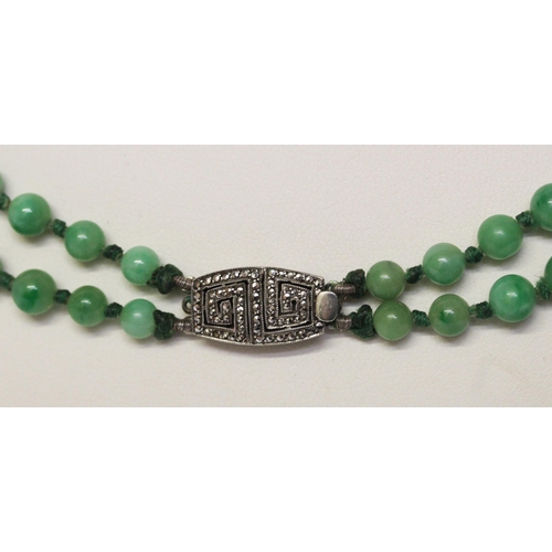 678 - An Art Deco double graduated row of jade beads with silver and marcasite deco Greek key design clasp... 