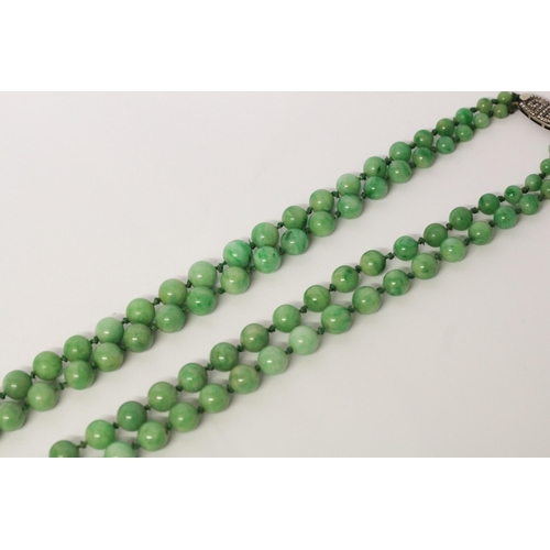 678 - An Art Deco double graduated row of jade beads with silver and marcasite deco Greek key design clasp... 