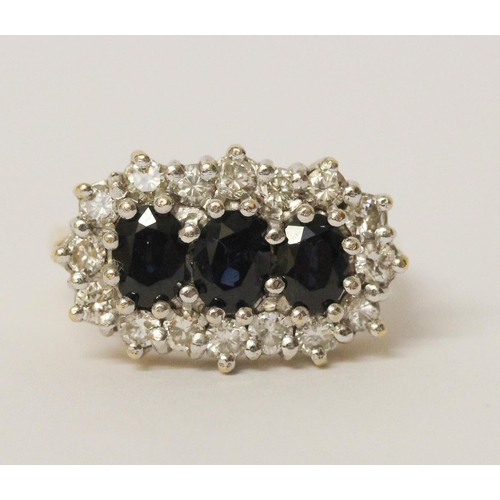 719 - A three stone sapphire and diamond ring, the three oval sapphires surrounded by a cluster of brillia... 