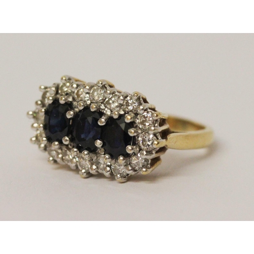 719 - A three stone sapphire and diamond ring, the three oval sapphires surrounded by a cluster of brillia... 