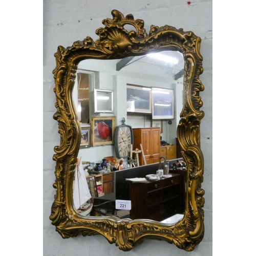 221 - A shaped wall mirror in decorative gilt frame