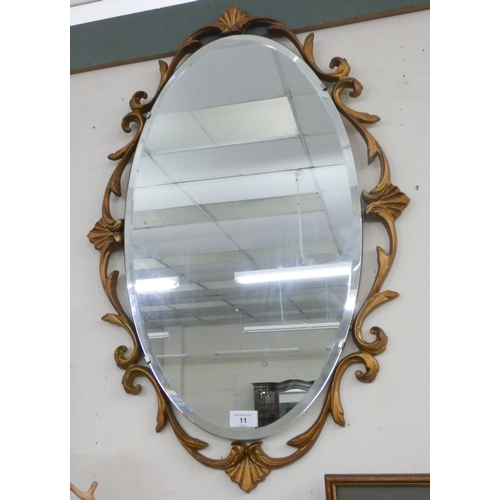 11 - An oval bevelled mirror in decorative gilt frame