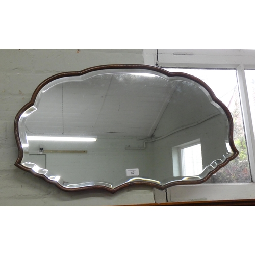 40 - A shaped bevelled wall mirror in oak frame