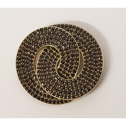 615 - A large Bohemian garnet knot design brooch in yellow metal unmarked, 6cms diameter