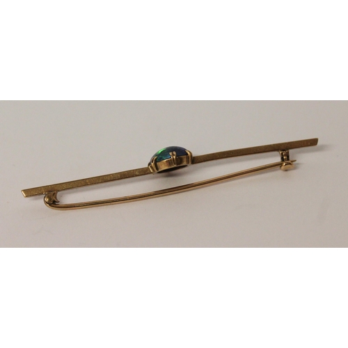 639 - An opal bar brooch, with claw set opal with good play of colour to the centre of unmarked yellow met... 