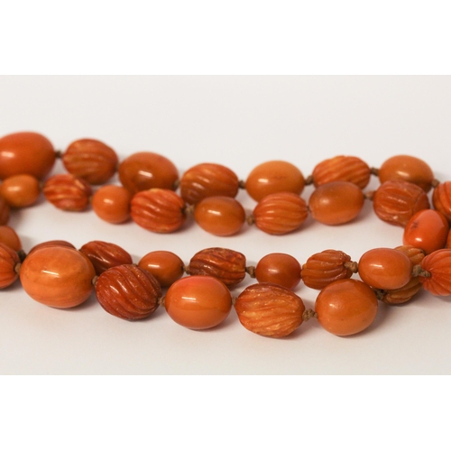 650 - Long vintage row of amber beads, the row individually knotted of oval carved and plain beads. Weight... 