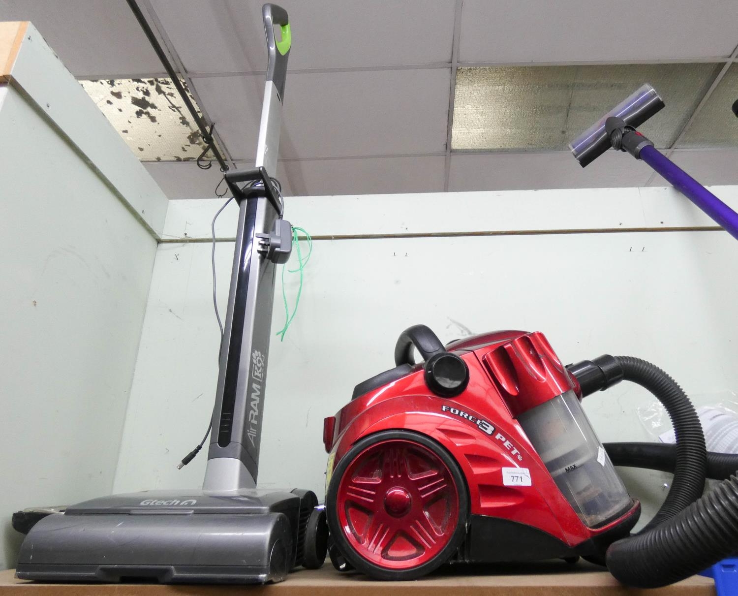 A GTech Air Ram Canine cordless rechargeable vacuum cleaner and a red