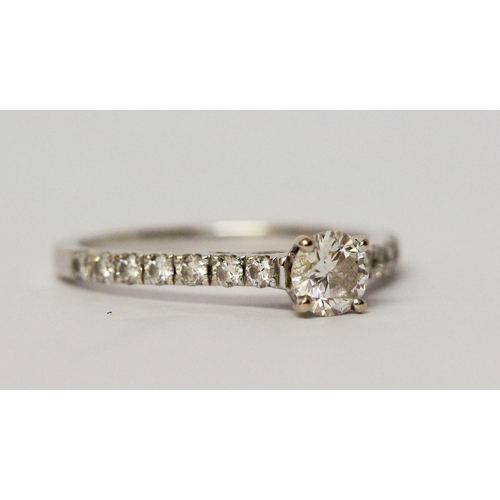 545 - A modern diamond engagement ring, with a circular brilliant cut diamond in claw setting on brilliant... 