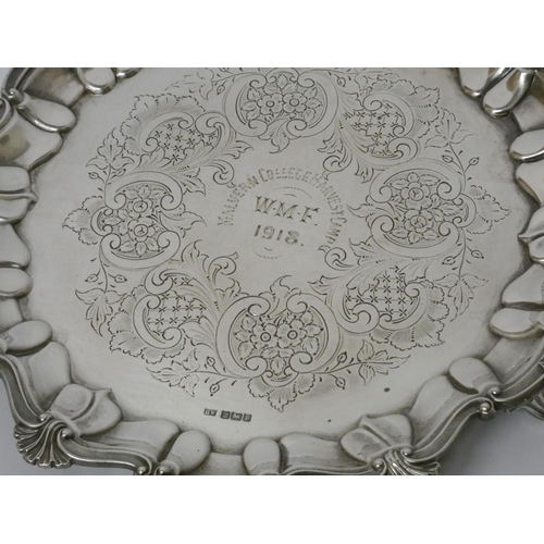 684 - A silver card waiter of small salver, with decorative cast shell border, engraved with presentation ... 