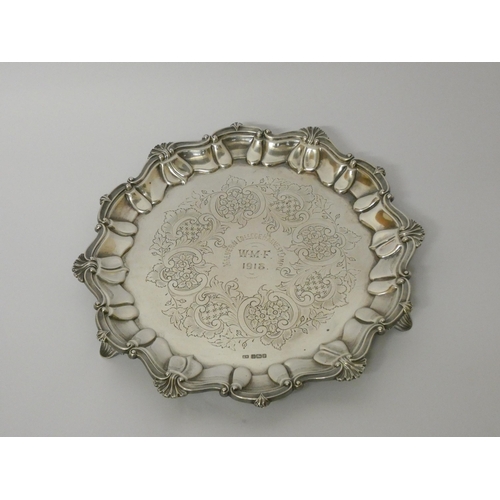 684 - A silver card waiter of small salver, with decorative cast shell border, engraved with presentation ... 