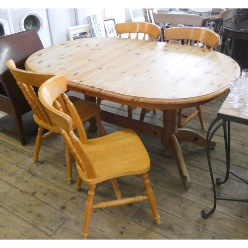 64 - An oval pine extending dining table with centre leaf and four spindle back Windsor style chairs