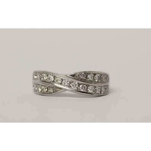 506 - A diamond channel set cross over design band ring. On unmarked white precious metal. Ring size K, we... 