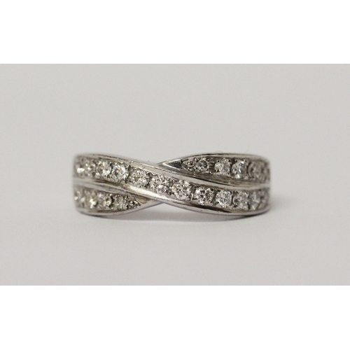 506 - A diamond channel set cross over design band ring. On unmarked white precious metal. Ring size K, we... 