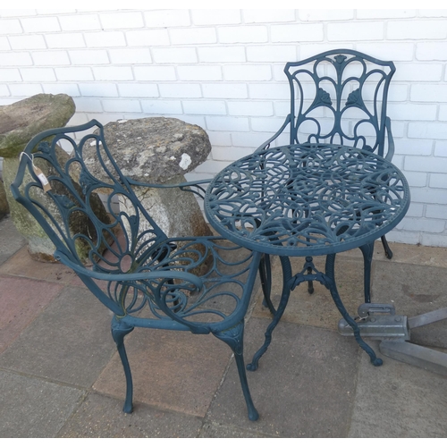 710B - A green painted circular metal garden table together with two matching chairs