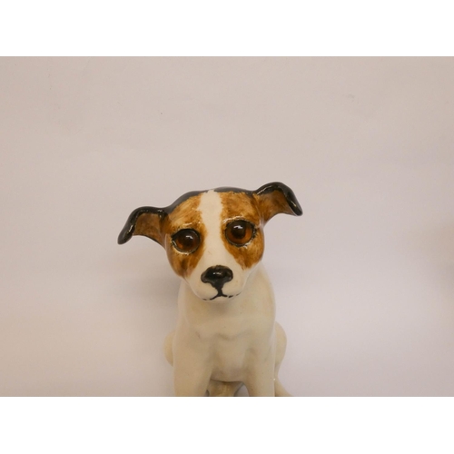 241 - A Winstanley pottery figure of a seated Jack Russell puppy with amber glass eyes, 23cms tall