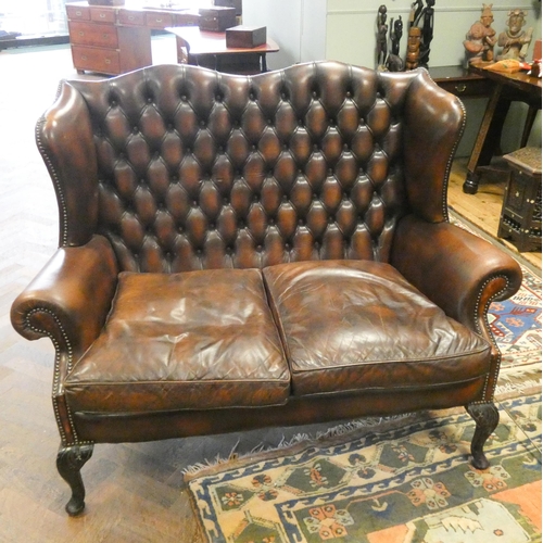 322 - A pair of brown leather buttoned wing backed settees standing on cabriole legs with matching stool