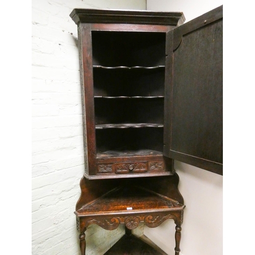 275 - A late Victorian carved dark oak corner cabinet standing on a two tier table style base