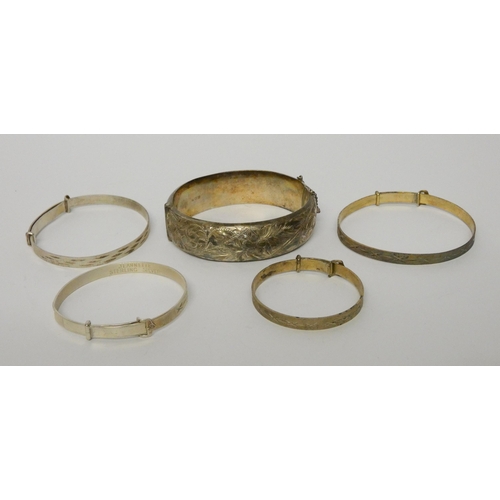 524 - A wide silver hinged bangle and four further christening bangles