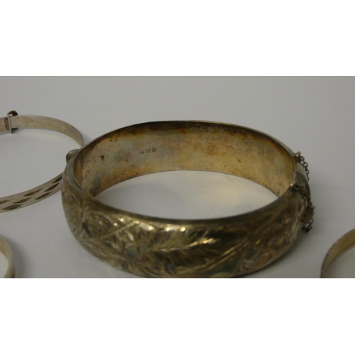 524 - A wide silver hinged bangle and four further christening bangles