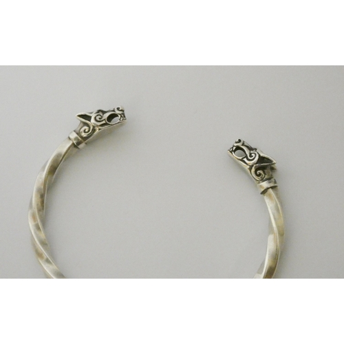 627 - A silver torque twist bangle with wolf head finials.