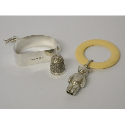 507 - A child's teething ring with silver teddy bear rattle, a silver novelty napkin ring modelled as a du... 