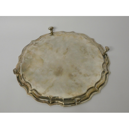 514 - A silver salver with simple pie crust edge, resting on four scrolled feet, 25 cms diameter. Sheffiel... 