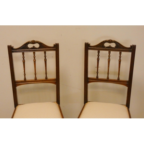 57 - A pair of Edwardian walnut spindle back bedroom chairs with cream upholstered seats standing on reed... 