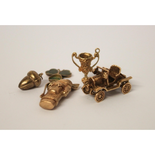 414 - Hallmarked 9ct gold bag of golf clubs charm, vintage car charm, trophy cup,  acorn and a clover leaf... 