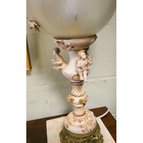 76 - A decorative cherub mounted table lamp with floral decorated globe shade, 26