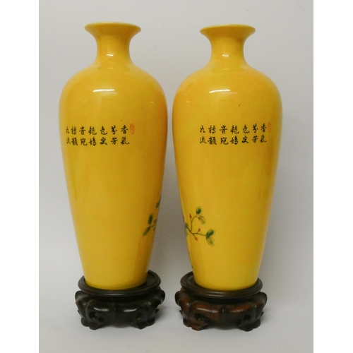 177 - A pair of Chinese yellow bird and floral decorated vases with wooden stands, 11 1/4