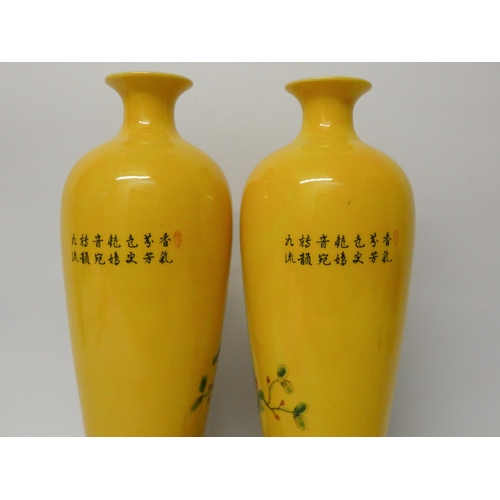 177 - A pair of Chinese yellow bird and floral decorated vases with wooden stands, 11 1/4