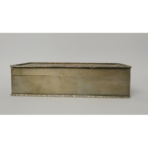 531 - A silver cigarette box, with engine turned detail and cast edge, the hinged lid with gilded interior... 