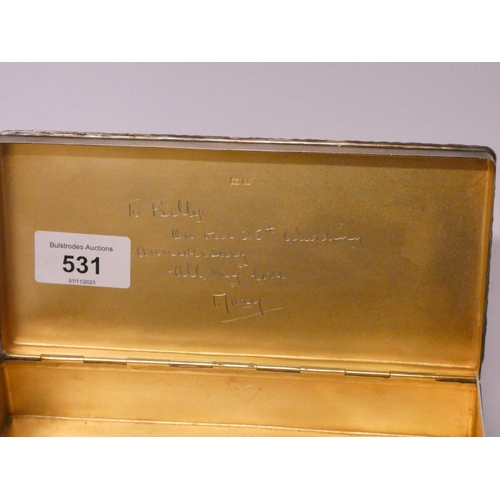 531 - A silver cigarette box, with engine turned detail and cast edge, the hinged lid with gilded interior... 