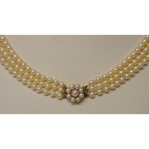 438 - A triple row cultured pearl necklace, individually knotted, to a pearl cluster and gold clasp, in Je... 