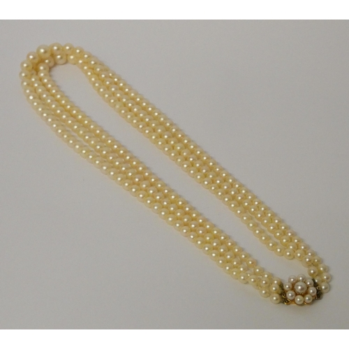 438 - A triple row cultured pearl necklace, individually knotted, to a pearl cluster and gold clasp, in Je... 