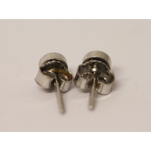 483 - A pair of diamond stud earrings in platinum rub over settings