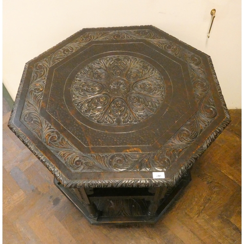 137 - An octagonal carved dark oak centre table with under tiers, 34