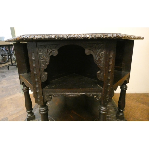 137 - An octagonal carved dark oak centre table with under tiers, 34