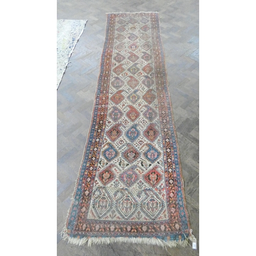 178 - A Persian wool pile carpet runner decorated with medallions and borders - a very worn patch to one e... 