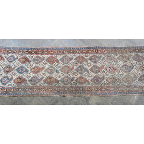 178 - A Persian wool pile carpet runner decorated with medallions and borders - a very worn patch to one e... 