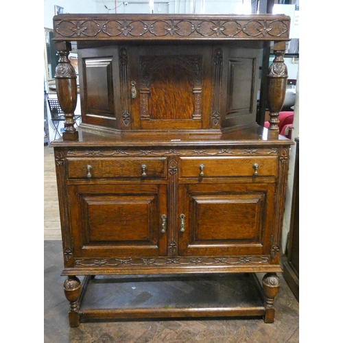 134 - An antique style oak court cupboard with shaped cabinet back, drawers and cupboards under on carved ... 