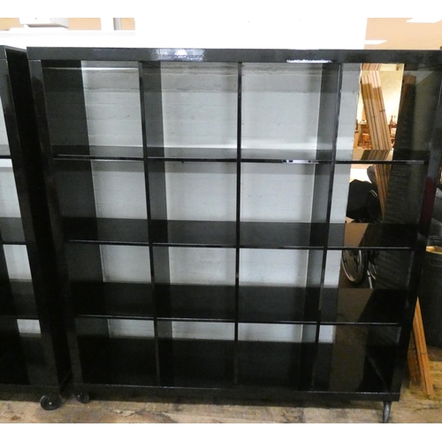 62 - A modern gloss black cube style display unit/room divider, of  sixteen partitions on castors, 64