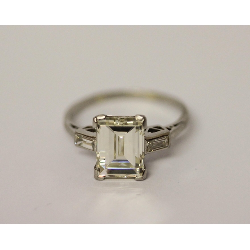 450 - An Art Deco solitaire diamond ring, the emerald cut diamond weighing approximately 3 carats, claw se... 