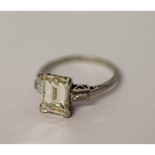 450 - An Art Deco solitaire diamond ring, the emerald cut diamond weighing approximately 3 carats, claw se... 