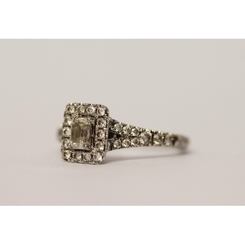 383 - A platinum and diamond ring, with an emerald cut diamond to the central rectangular panel, surrounde... 