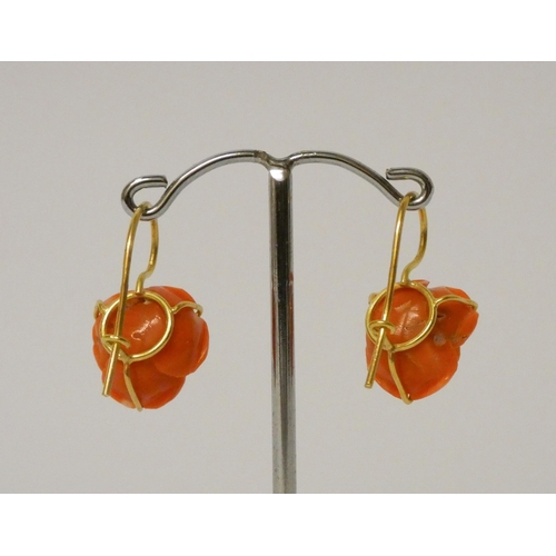 417 - A pair of carved coral rose drop earrings, on 18ct yellow gold wire fittings. 28mm drop.