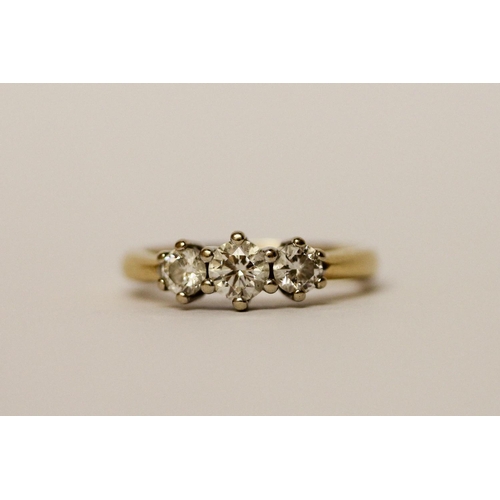 446 - A three stone diamond ring, three brilliant cut circular diamonds on an 18ct yellow gold band, Diamo... 